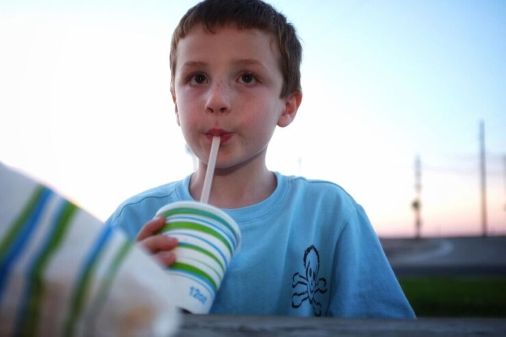 a child using a straw to drink juice- pediatric dentist Dallas, TX